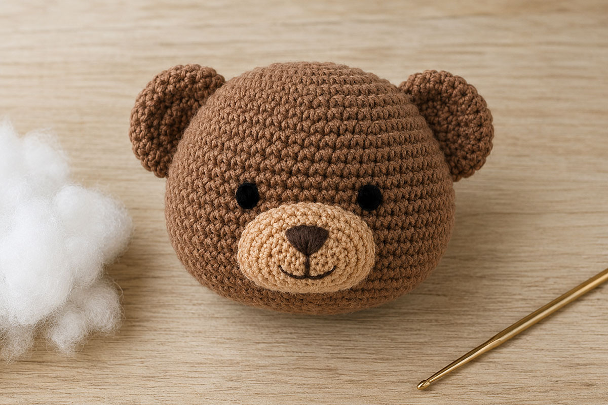 Brown crochet teddy bear head with tan muzzle black satin stitch eyes and embroidered dark brown nose and mouth