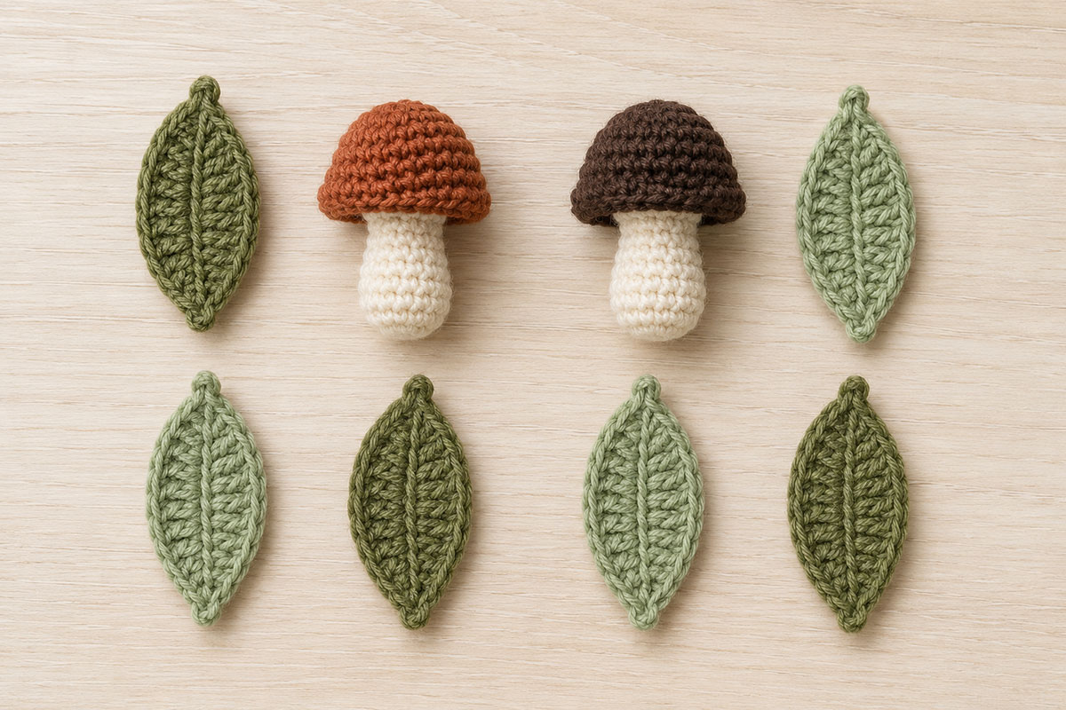 Two small crochet woodland mushrooms and six green leaves ready for baby mobile assembly