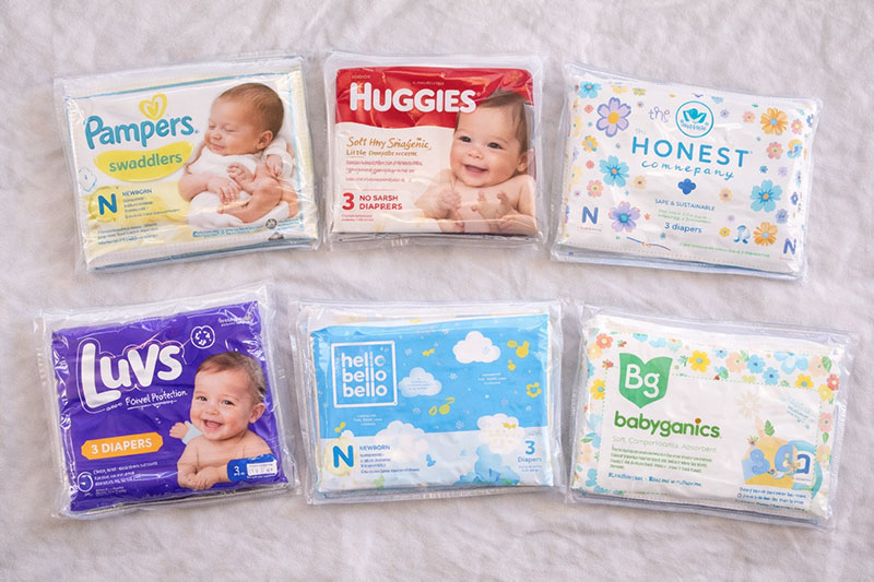 Assorted newborn diaper sample packs from different brands laid out side by side