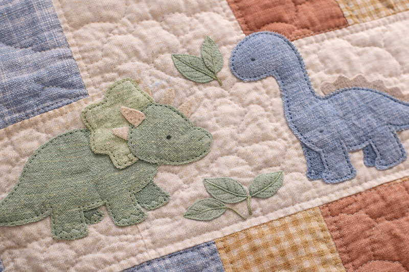 Close-up of appliqué dinosaur quilt block with clean neutral stitching