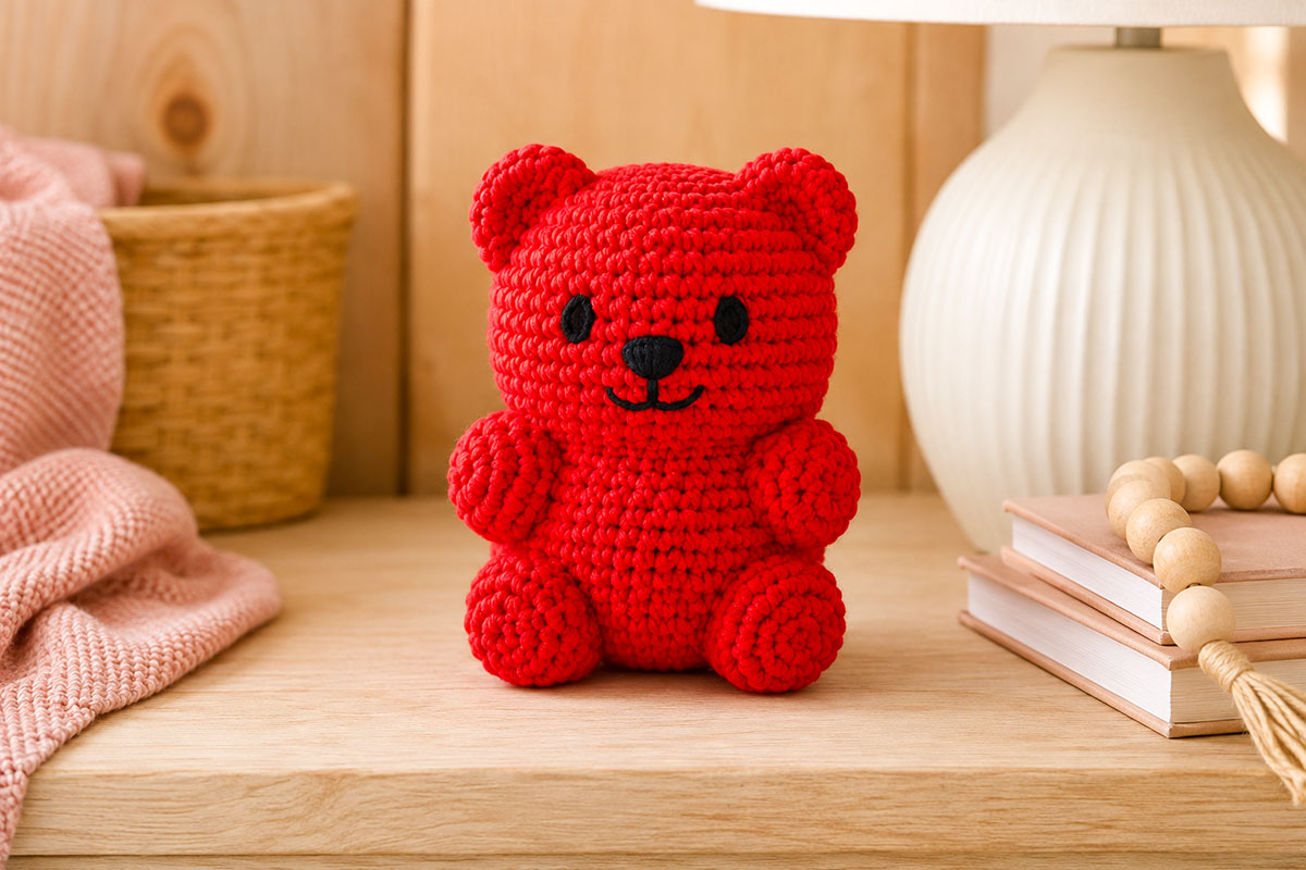 Finished bright single color crochet gummy bear displayed upright with a rounded candy shaped head tiny ears short arms plump body and stubby feet