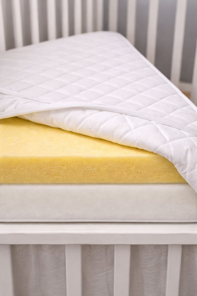 Firm foam crib mattress core shown under a quilted cover to illustrate supportive structure