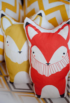 A pair of colorful stuffed toy foxes in red and yellow