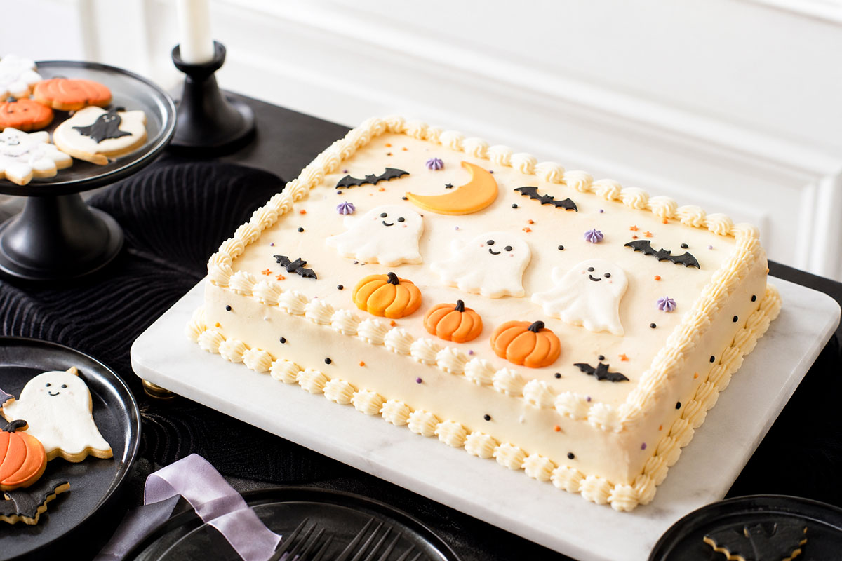 Halloween baby shower sheet cake with piped ivory border, friendly ghosts, orange pumpkins, bats and moon details