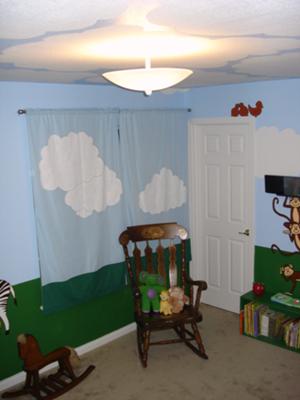 The homemade nursery curtains have hand-painted clouds to match the blue sky in the jungle theme nursery wall mural