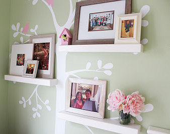 Family photos displayed on shelves in the branches of a tree nursery wall mural