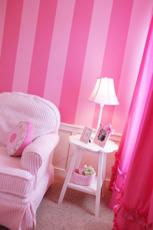 Pink striped baby girl nursery walls with ruffled fuchsia curtain panels and chenille chair and ottoman