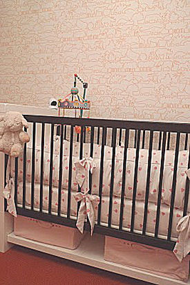 Pink orange and white baby girl nursery room with a modern Maclaren Netto crib and Porthault linens