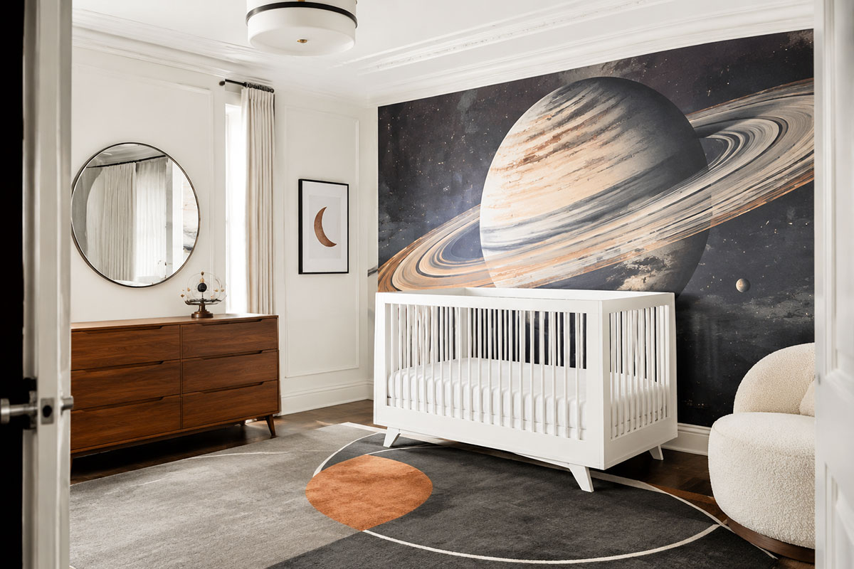 Modern space themed nursery with an oversized Saturn mural, white crib, walnut dresser and minimal celestial accents