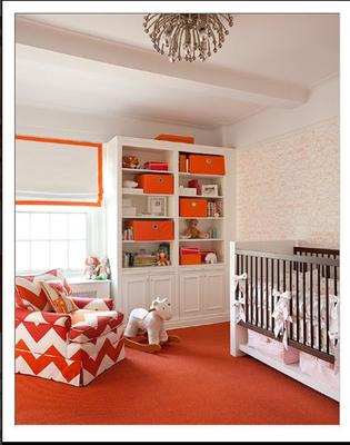 Pink white and orange baby room for a girl with a nursery chair upholstered in orange and white chevron fabric.