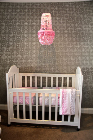 Pink capiz shell nursery chandelier in a modern pink and gray baby girl nursery room with gray and white geometric pattern wallpaper