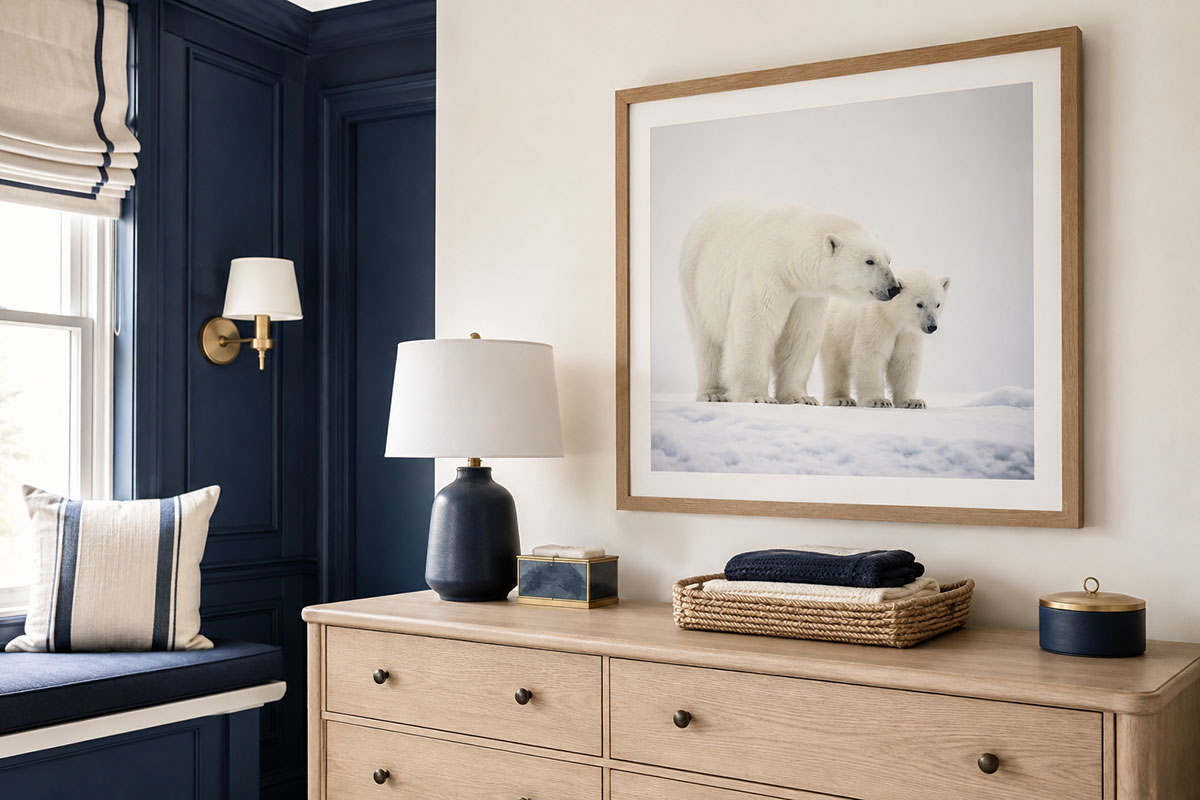 Warm white and navy blue polar bear nursery wall with natural wood framed bear artwork beside a light wood dresser