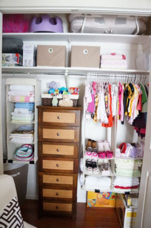 Beautifully organized baby girl nursery closet with shelves cubby holes and drawers