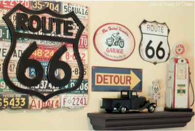 Gallery wall art display in a baby boy's Route 66 nursery theme including vintage road signs and service station memorabilia