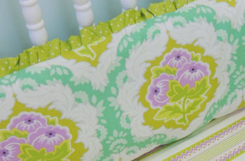 A baby girl's bedding set with ruffles in orchid purple, emerald green and gold.  