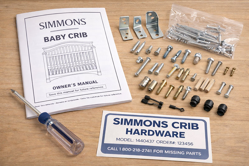 Simmons crib hardware including bolts, brackets, and conversion rails laid out for identification