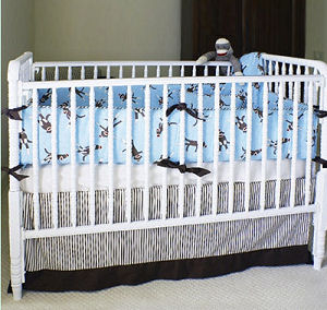 Sock monkey baby crib bedding set with a baby blue, brown and red quilt and fitted crib sheets and striped mattress ticking bed skirt with gray stripes in a neutral nursery
