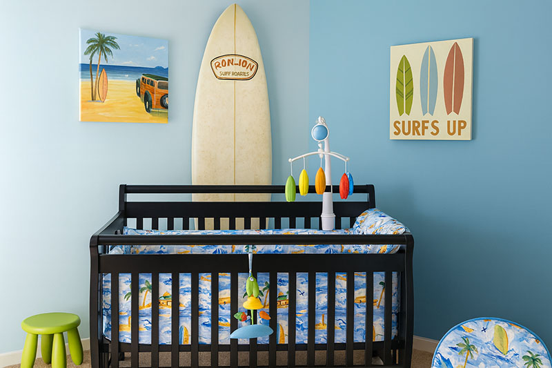 Updated surf themed nursery with modern beach artwork and surfboard mobile in cool natural daylight