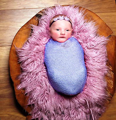 Blue newborn baby swaddling blanket layered onto purple faux fur and rustic wood first portrait photo prop idea.