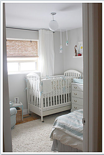 The serene, light blue brown and greige baby boy nursery room features unique storage features without sacrificing style