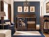 Blue and brown baby boy nursery with dark wood crib, handmade safari animal bedding, leopard-print curtains, giraffe lampshade and navy upholstered chair.