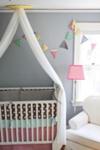 A shared baby nursery with colorful pennants and crib bedding set 