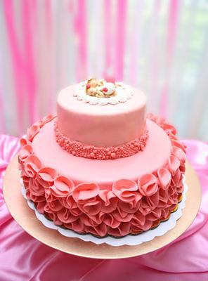 Homemade pink baby shower cake for twin girls with ruffles and homemade fondant sleeping baby cake topper.