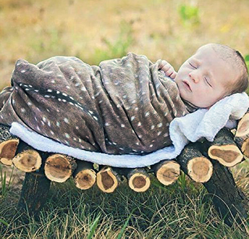 Woodland forest theme baby photo prop posing idea.  Newborn baby photo idea with deer skin and handmade log crib outside in fall.