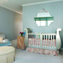 A baby nursery with blue wall paint color, pink flowered ceiling border and metallic silver painted sleigh crib for a girl