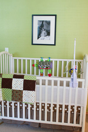 Green, brown and white polka dot baby crib with breathable bumper and educational crib mobile