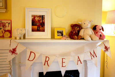 White wooden mantelpiece in Hadley's room decorated with DREAM bunting banner, framed artwork and stuffed toys