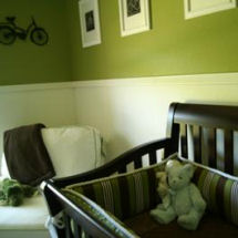 Vintage olive green and antique white baby nursery with black crib, teddy bear and bicycle art