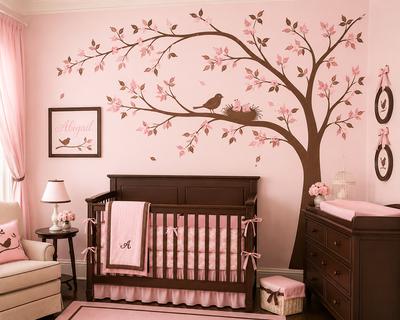 Elegant pink and brown bird-themed baby girl nursery with a hand-painted tree mural and mother bird perched on a branch above the crib