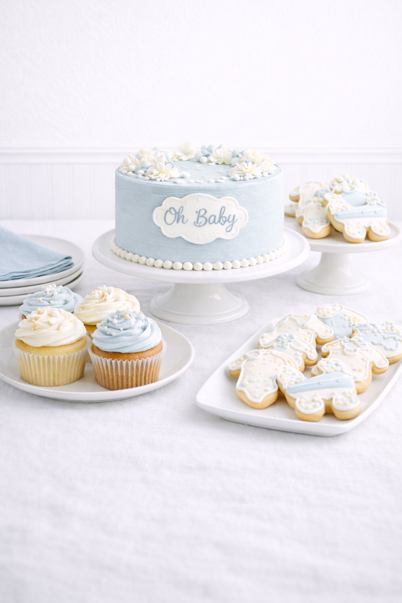 Baby shower dessert table with cake cupcakes and coordinated serving layout