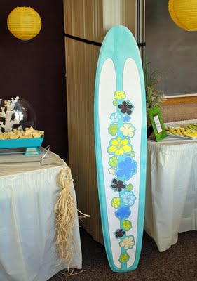 A surfboard decorated with hibiscus flowers added to the beach theme baby shower decorations