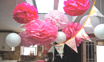 Hot pink and white tissue paper pom poms and party banner decorations for a baby girl shower