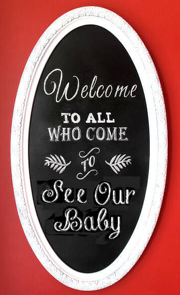 DIY chalkboard welcome sign in an oval frame for a baby nursery room