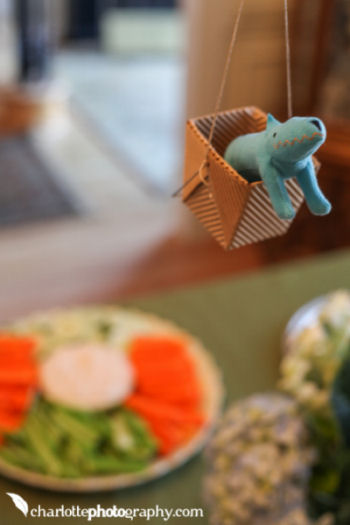 Colorful toy animals fill the baskets of the homemade hot air balloons decorating the area over the food table at the baby shower