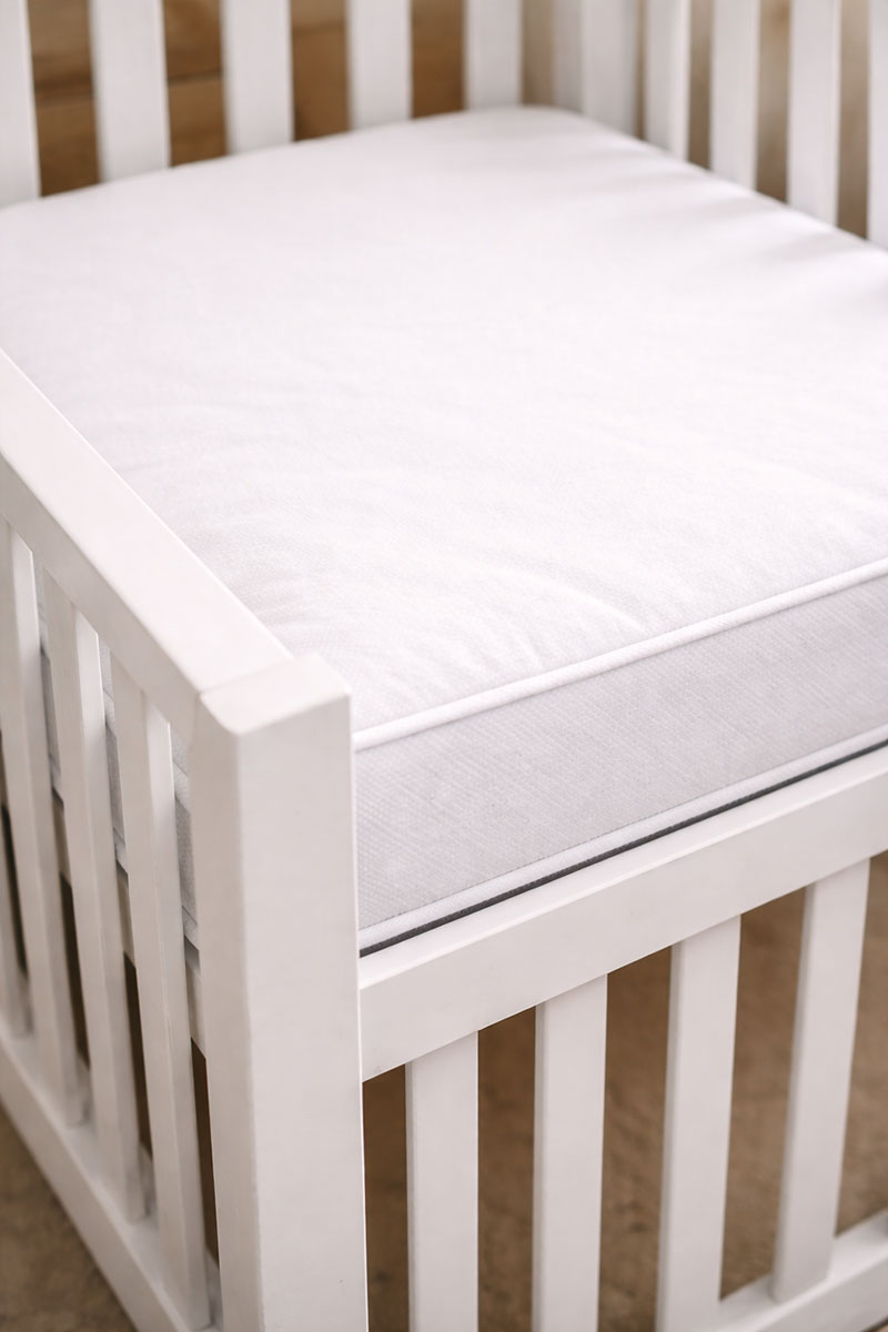 Corner view of crib mattress showing tight fit against crib rails with no gaps