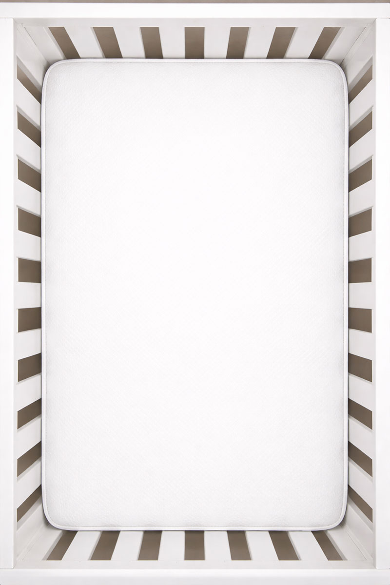 Crib mattress fitted tightly in a standard U.S. full-size crib with no visible gaps at the edges