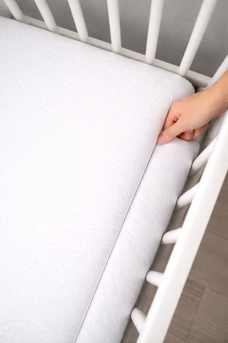 Top down view of crib mattress fitting tightly inside crib frame with no visible gaps along the rails