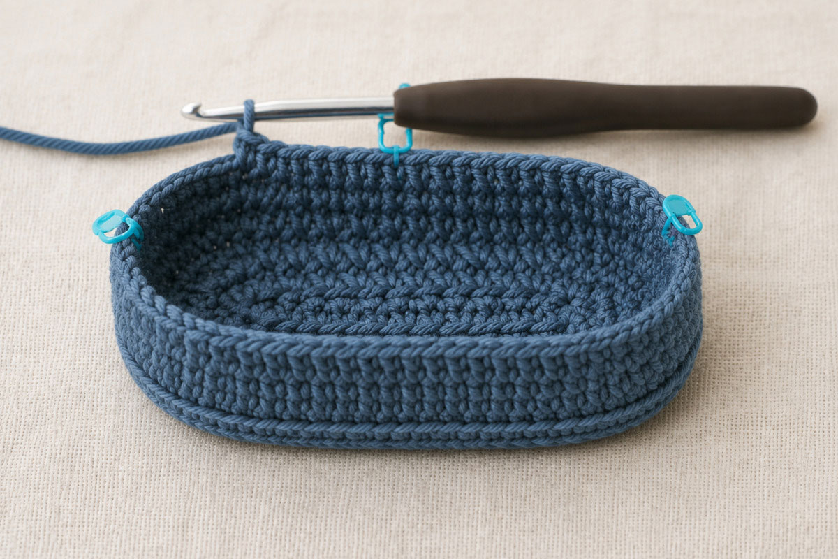 Crochet baby bootie with an oval sole, raised sidewalls and markers identifying the centered toe section
