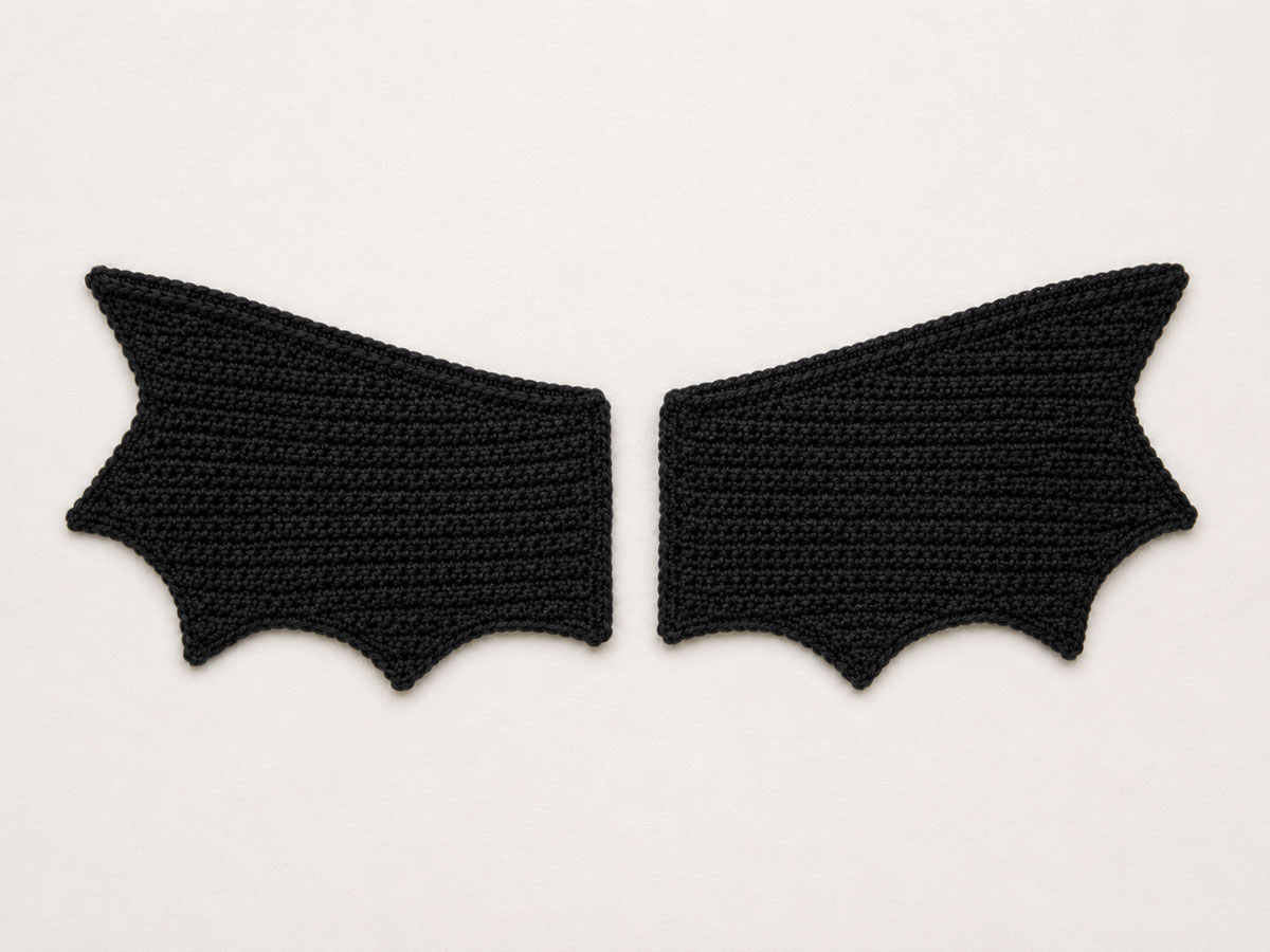 Two flat crochet bat wings with narrow inner edges and three shaped points along each outer edge