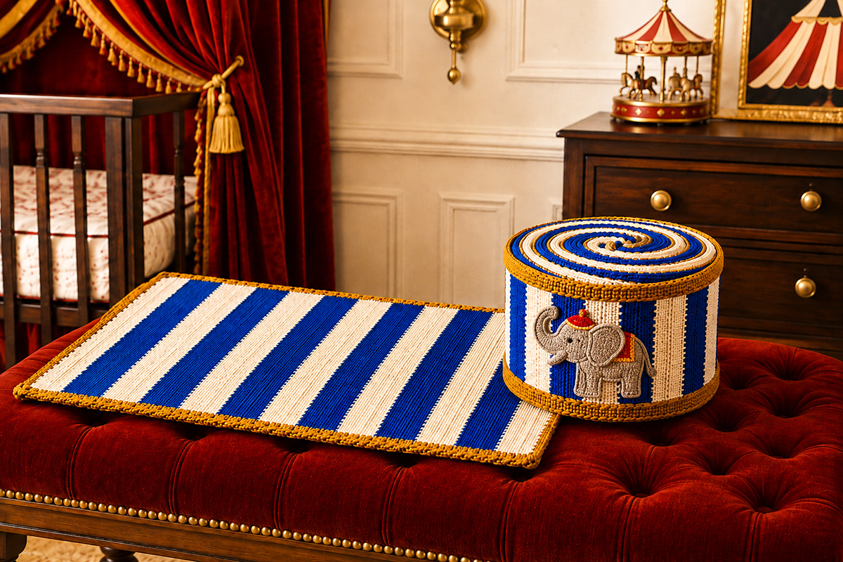 Royal blue and white crochet circus drum baby blanket with narrow antique gold braided-look edging shown flat beside the rolled drum form with two removable gold crochet keeper hoops and a sewn-on crocheted circus elephant appliqué in a vintage circus nursery