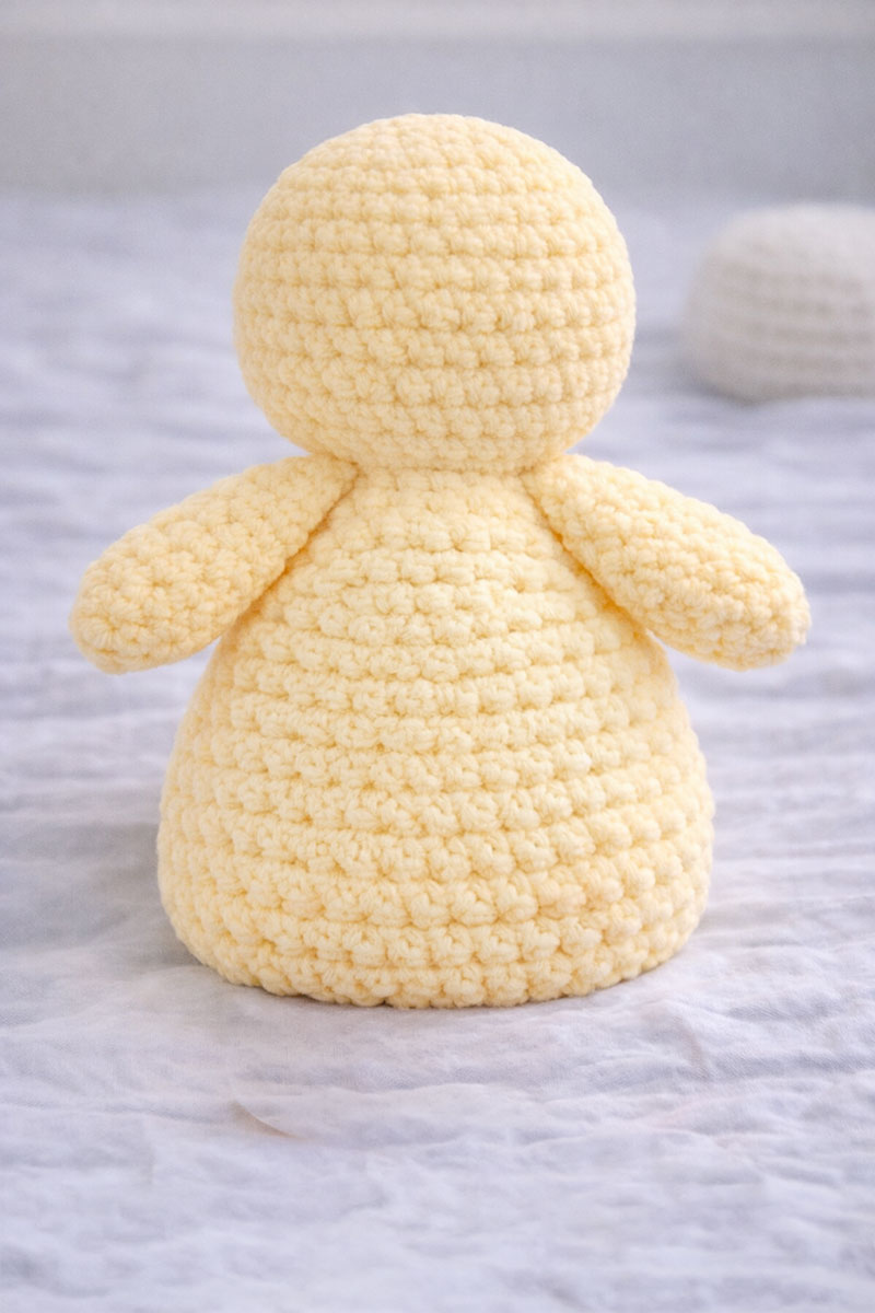 Back view of crochet duck lovey showing hollow shaped body and floppy wings