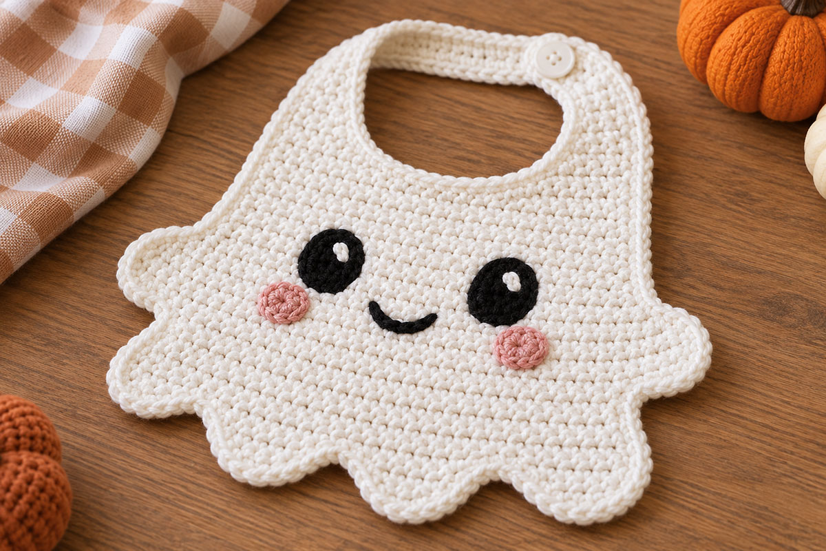Finished crochet ghost bib from a slight side angle showing the flat white body rounded side arm scalloped lower edge and buttoned neck strap