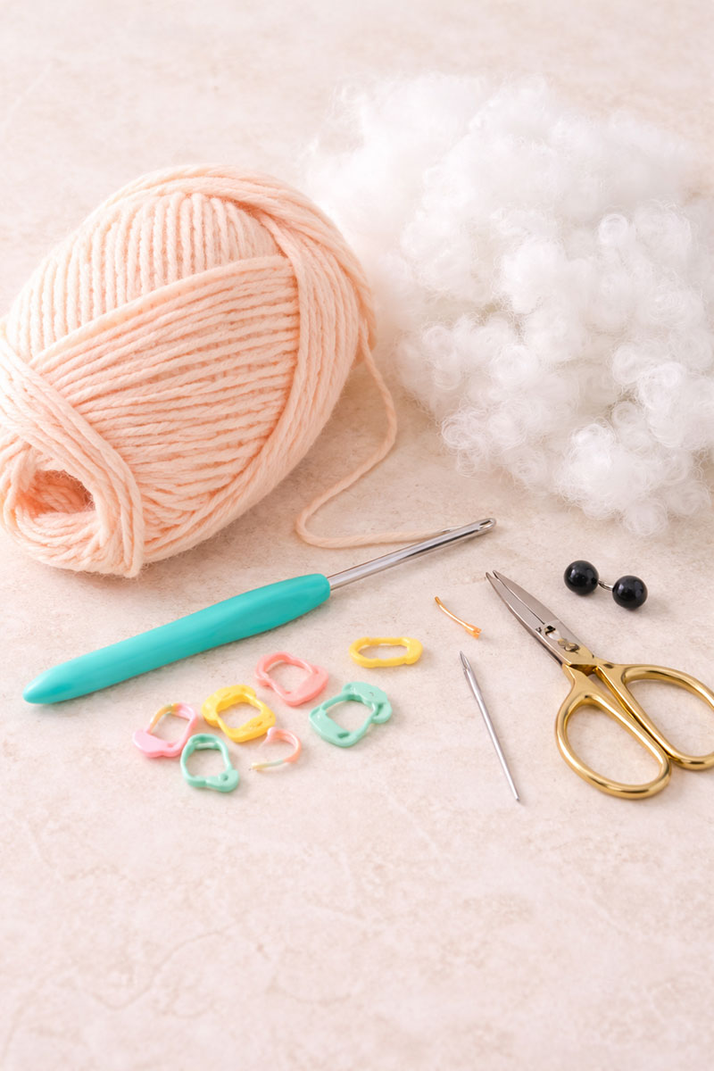 Supplies for a crochet jellyfish pattern including peach yarn hook stuffing and safety eyes