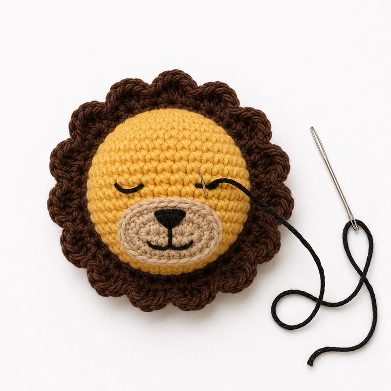 Crochet lion face embroidery showing stitched eyes nose and mouth