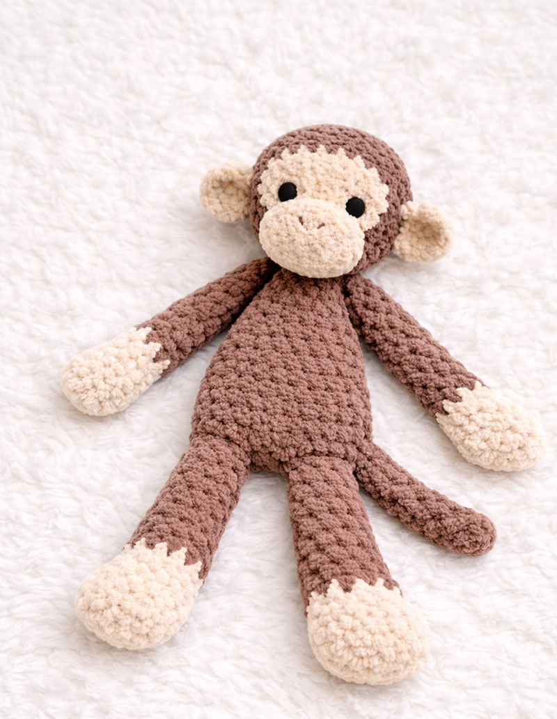 Finished crochet monkey lovey lying flat with relaxed limbs