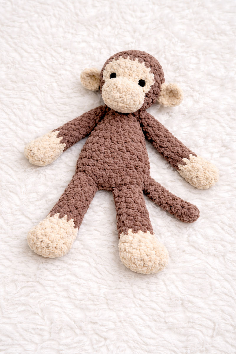 Crochet monkey lovey lying flat with long limbs and relaxed body shape